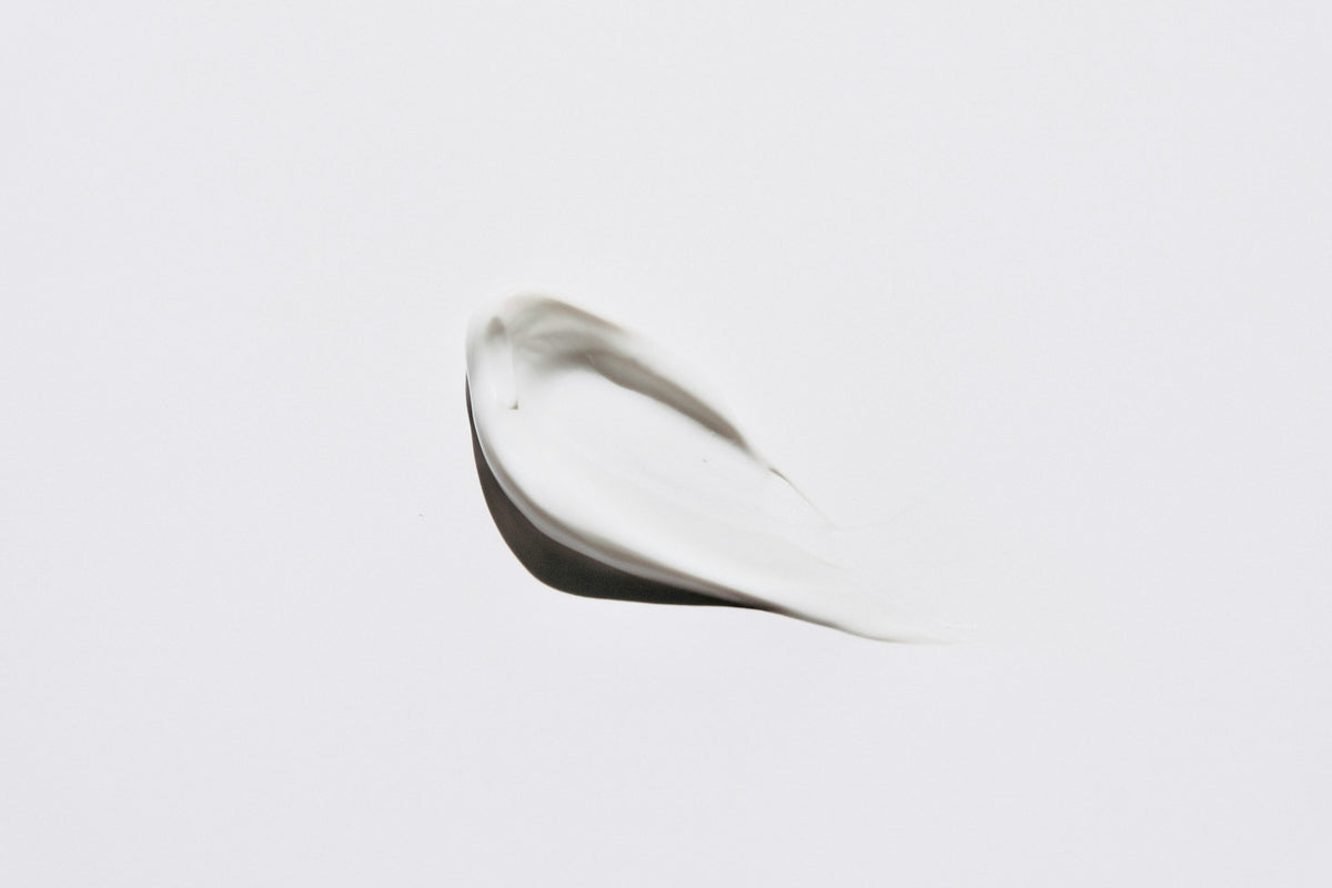 A smear of white cosmetic cream on a plain white background