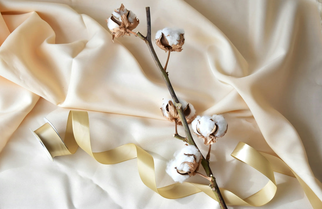 A branch of cotton and a ribbon on a bed